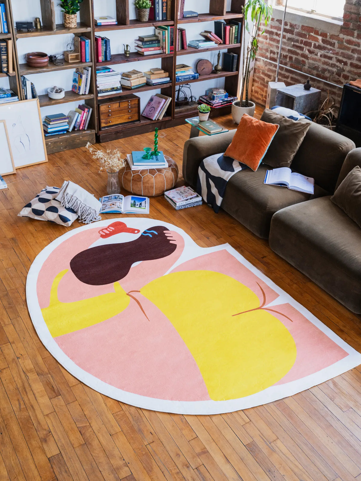 Funky body art rug with vivid abstract form, adding color contrast in a loft living room with bookshelves and a cozy sofa.