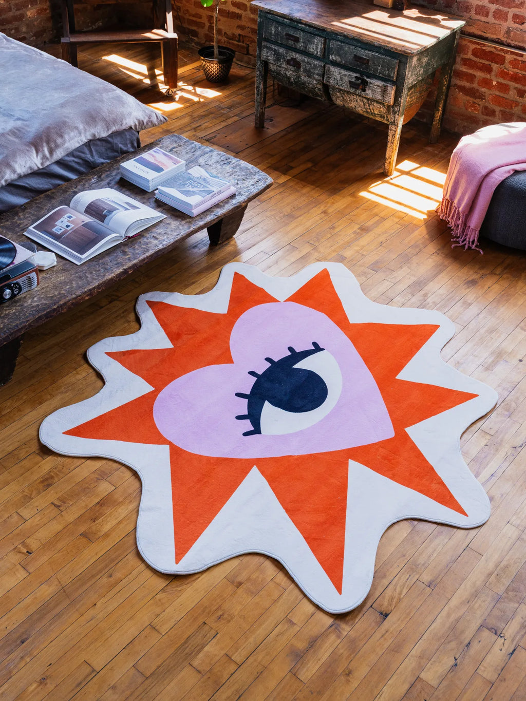 Heart Eye Rug by Megan Roy placed on wood floor beside a rustic bench with books
