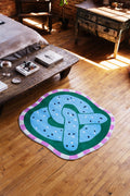 Pretzel-Shaped Cute Rug in blue shown on wood floor next to bed and long bench creating a bold accent in the bedroom