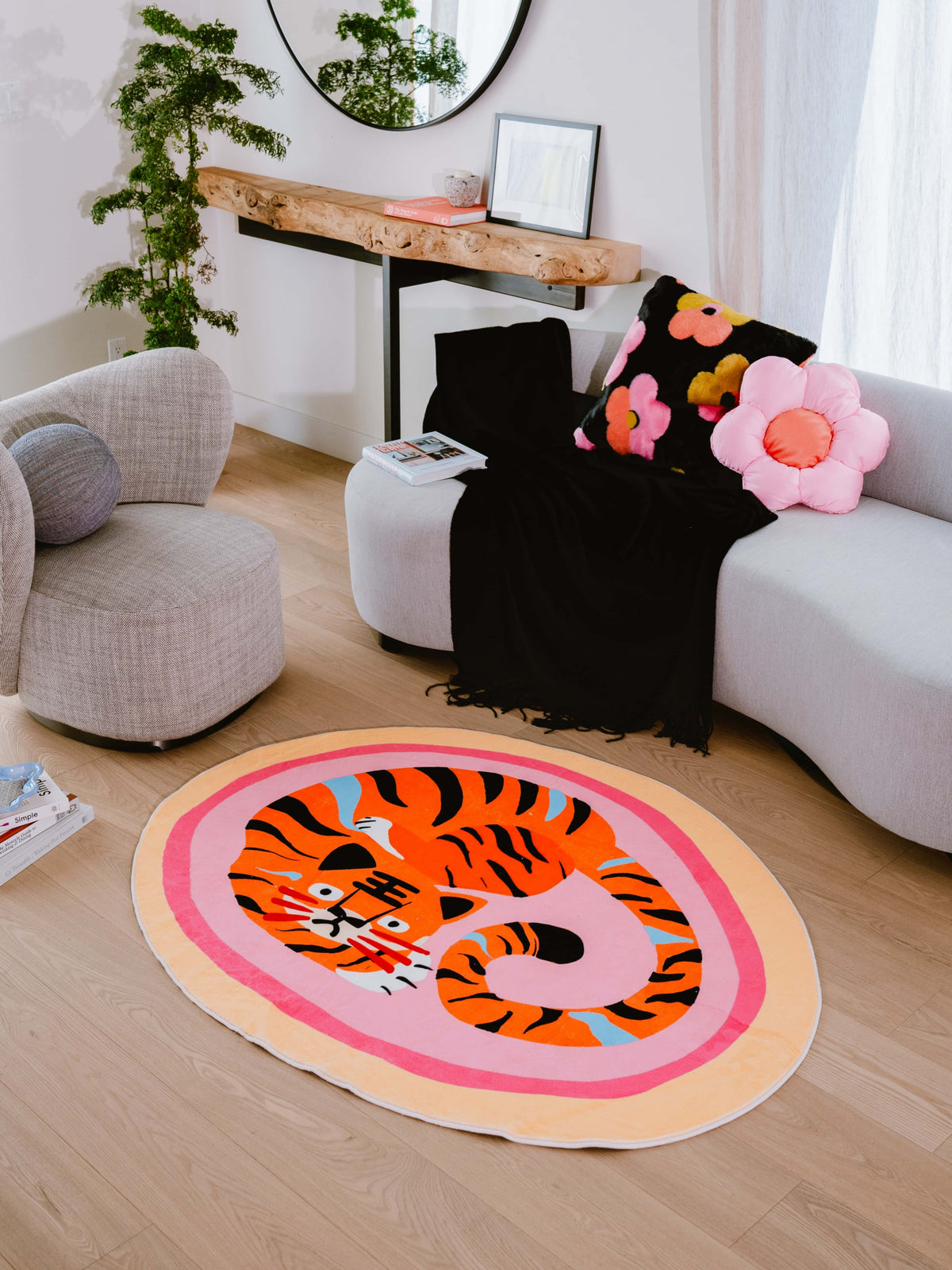 Pink base tiger rug pops in a light-filled lounge, balanced with curved furniture and whimsical flower cushions.