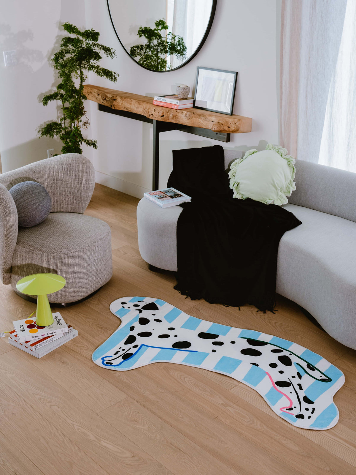 A living room featuring the Irregular Shaped Dog Runner Rug by Lu Yang, styled in front of a curved grey sofa with soft natural light.