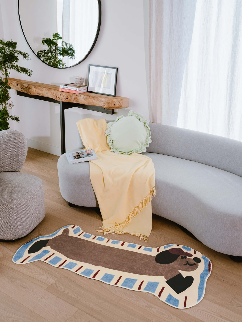 Irregular Shaped Brown Dog Runner Rug by Lu Yang styled in a cozy living room with light wood floor and curved grey sofa.