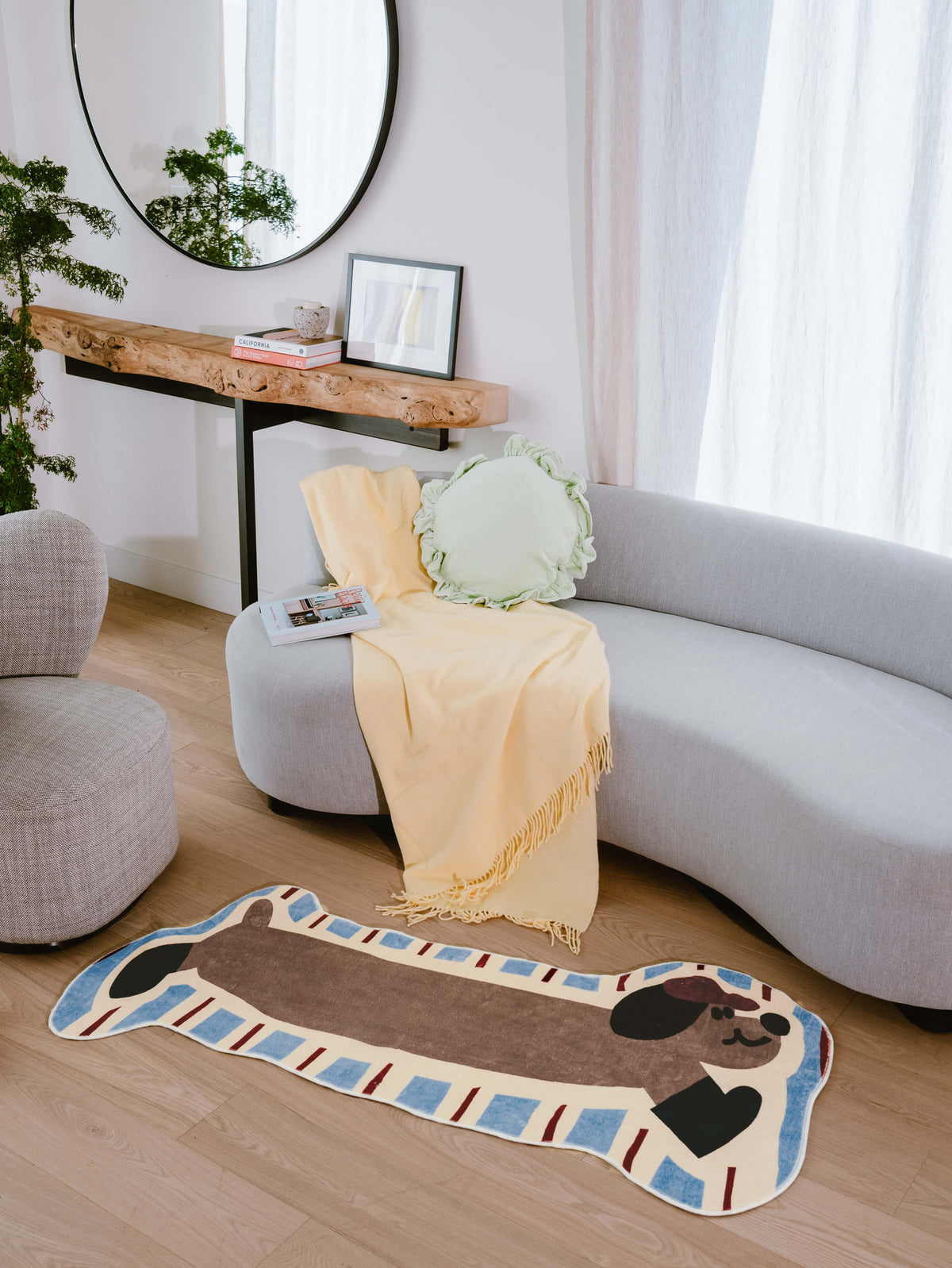 Irregular Shaped Brown Dog Runner Rug by Lu Yang styled in a cozy living room with light wood floor and curved grey sofa.