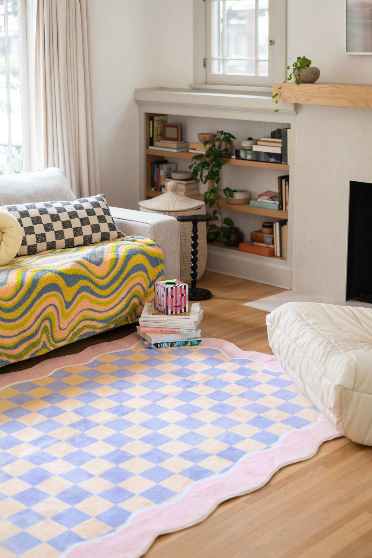 Mellow Pastel Rug in a cozy living room, styled with a wavy throw blanket and checkerboard pillow on a soft grey sofa.