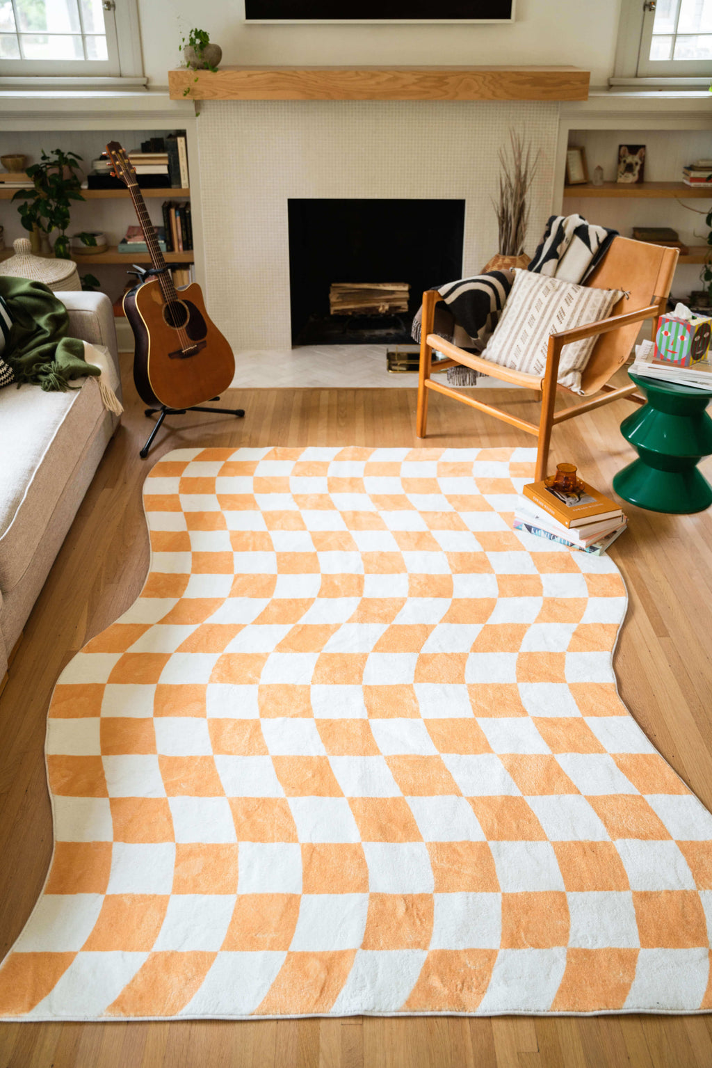 Living room with a Yellow Wavy Checkered Rug, placed in front of a fireplace and styled with a leather chair and green accent table.