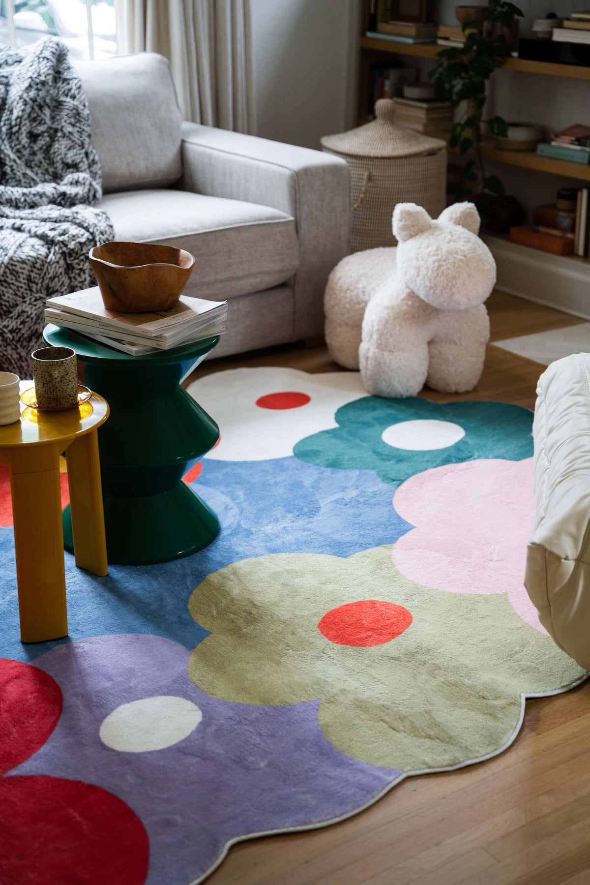 Funky Flowers Rug featuring bold, oversized blooms in a cozy living room with green and yellow accent tables and a plush white toy animal.