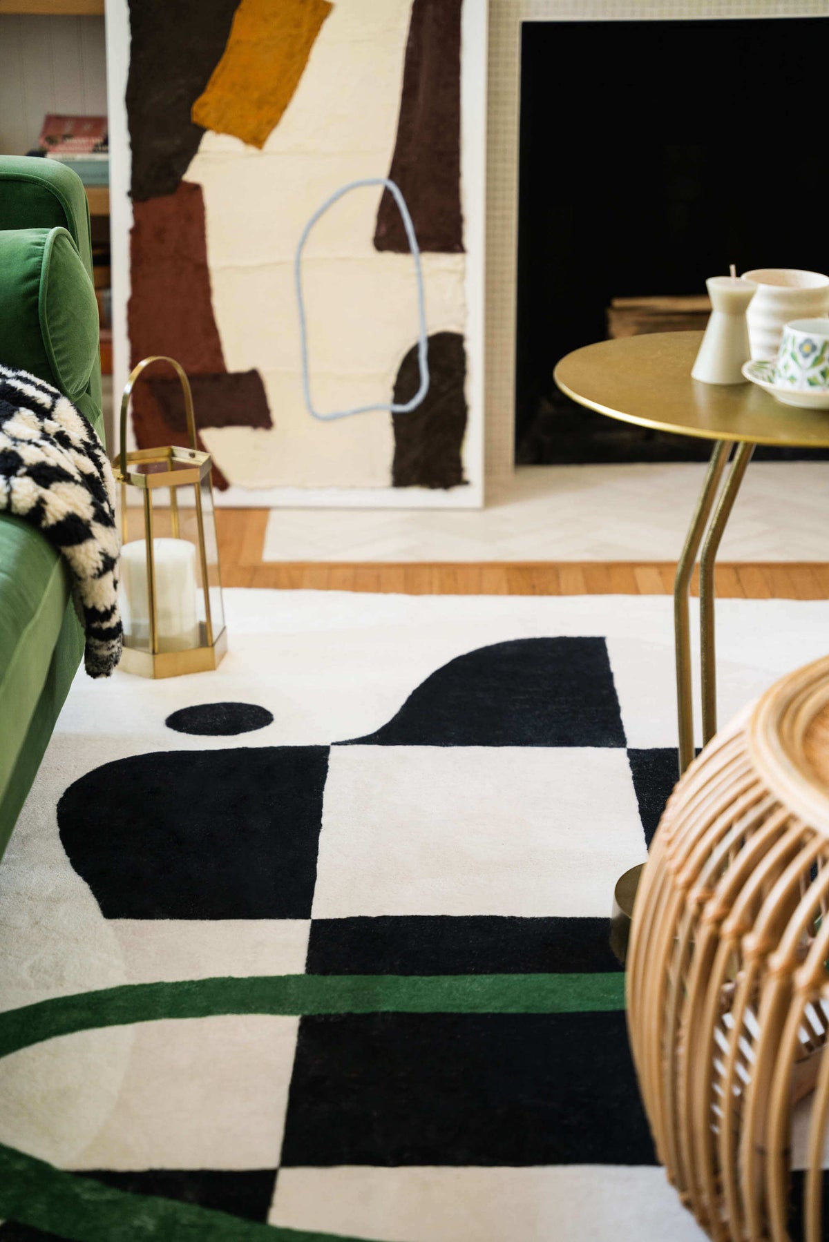Close-up of checkered rug's bold pattern beside a brass side table, rattan accents, and soft neutral furnishings.