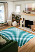 Vibrant Checkered Rug laid out in a cozy living room, styled with a green sofa, wooden floor, and decorative art and accents.