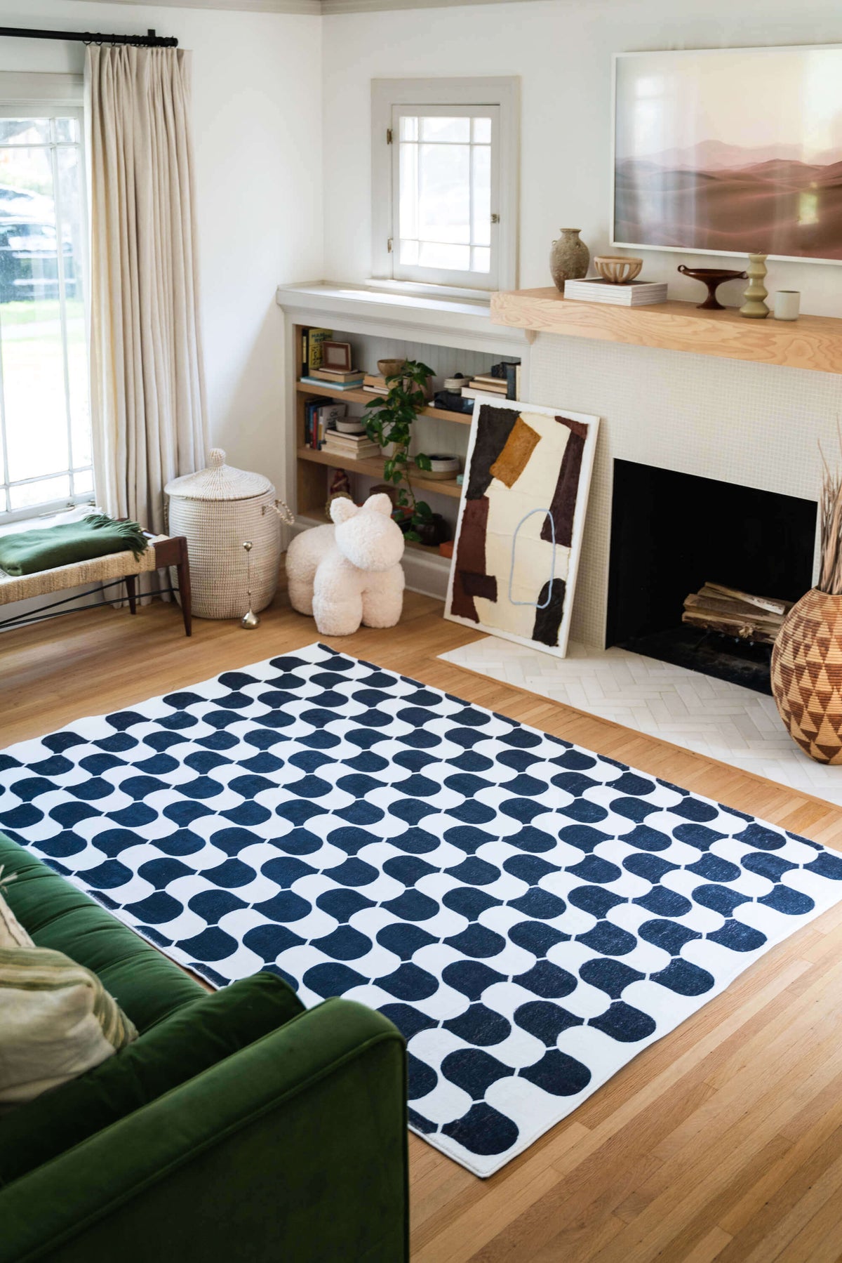 Black and White Wavy Rug styled in a cozy living room with a fireplace, green couch, and bookshelf.