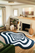 Black and White Vertigo Irregular Area Rug in a modern living room with fireplace and wood decor.
