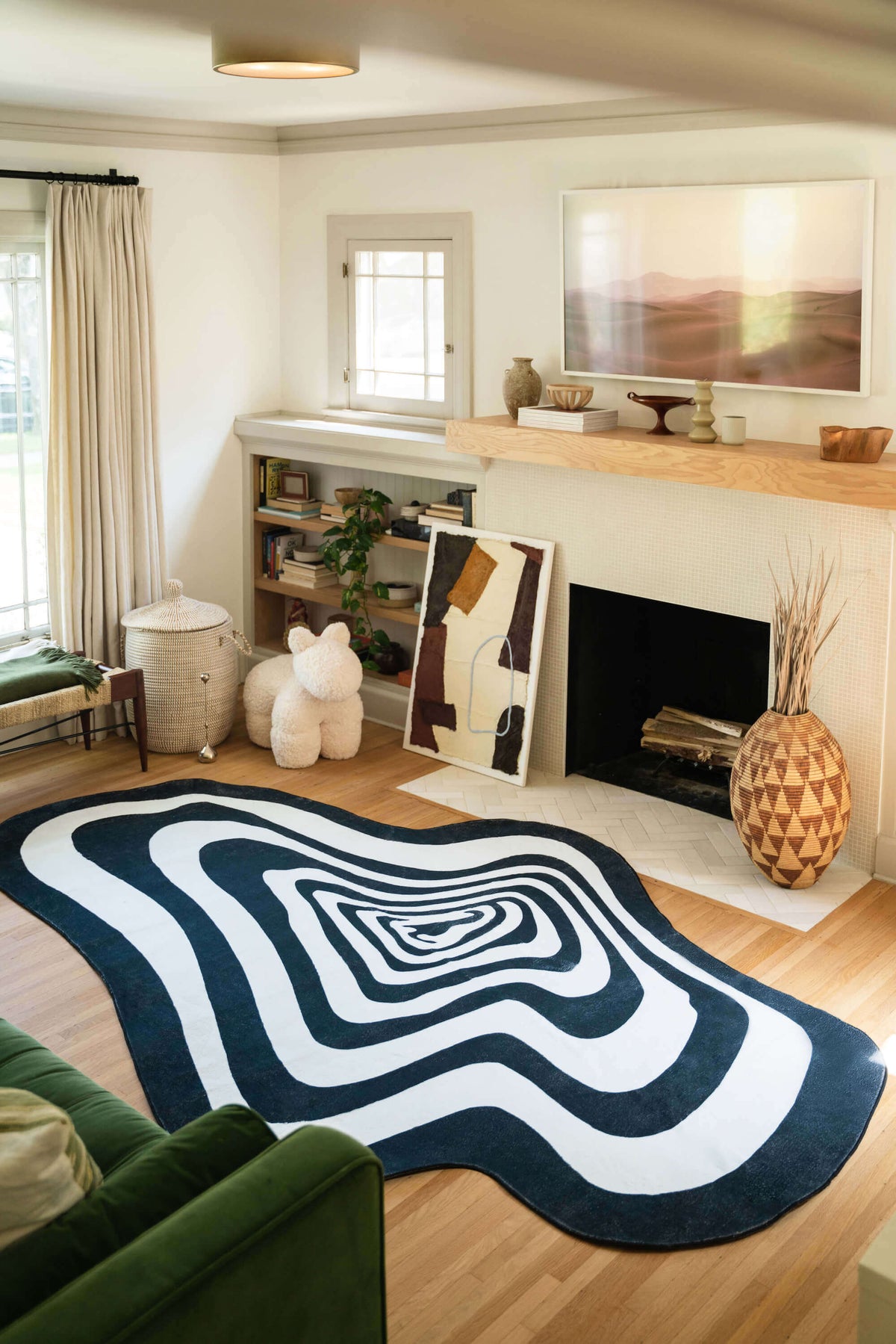 Black and White Vertigo Irregular Area Rug in a modern living room with fireplace and wood decor.