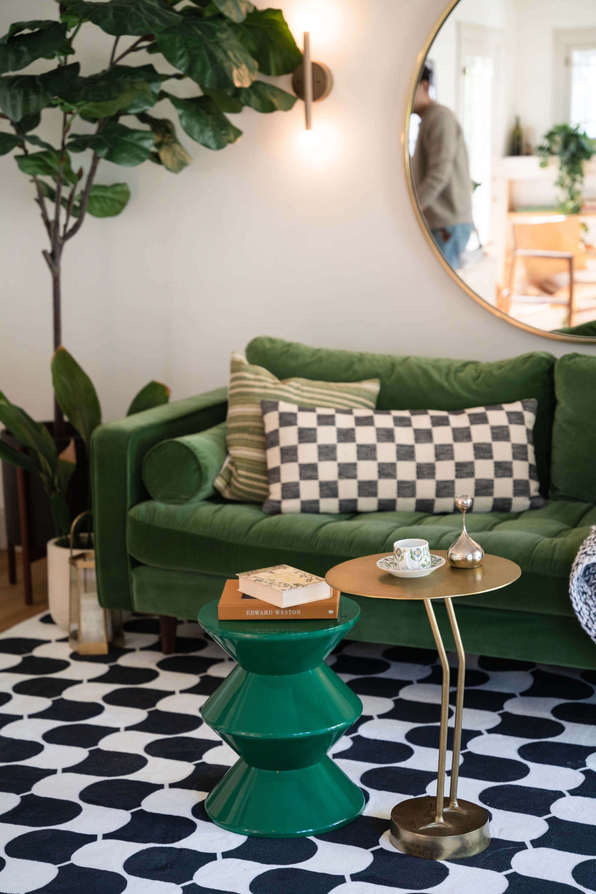 Close-up of the black and white wavy rug under green sculptural and brass side tables in a modern living space.