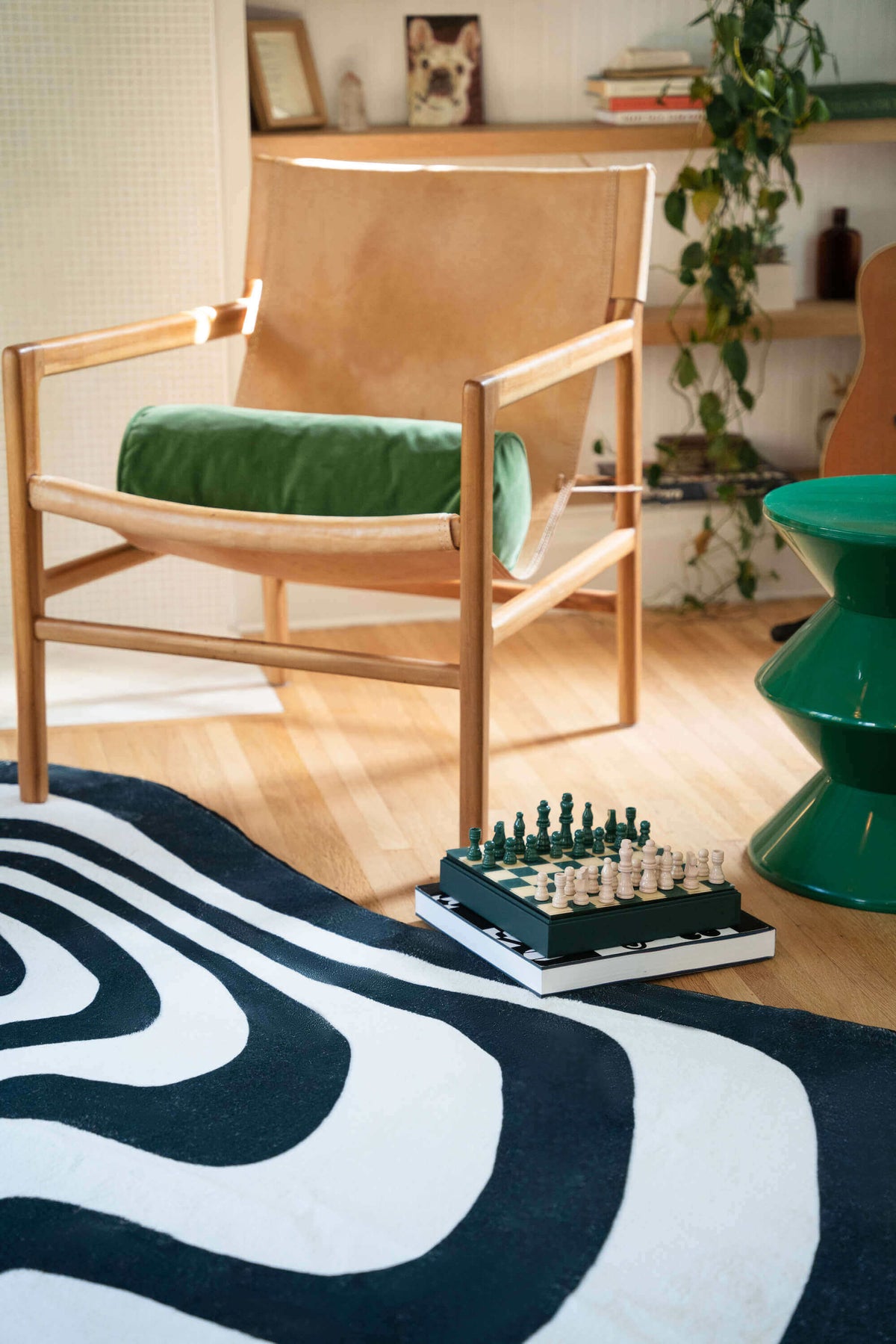 Close-up of the vertigo rug and chessboard near a tan leather chair on wooden floor.