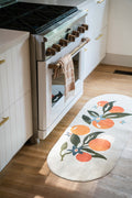 Orange Pattern Mat placed in front of a kitchen oven with white cabinetry and wooden floor.