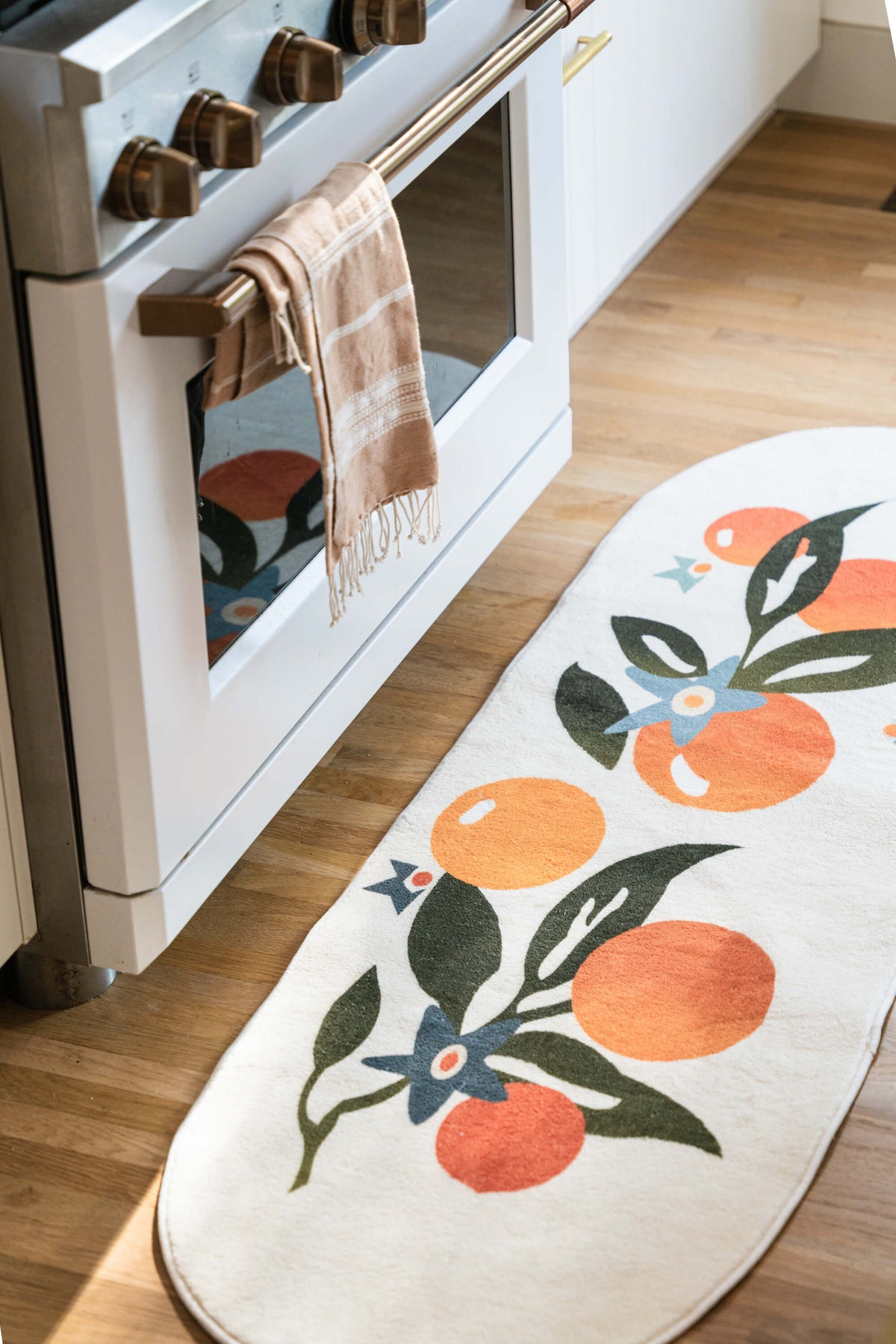 Close-up of the Orange Pattern Mat in the kitchen, showing detailed fruit and leaf motifs on wood floor.