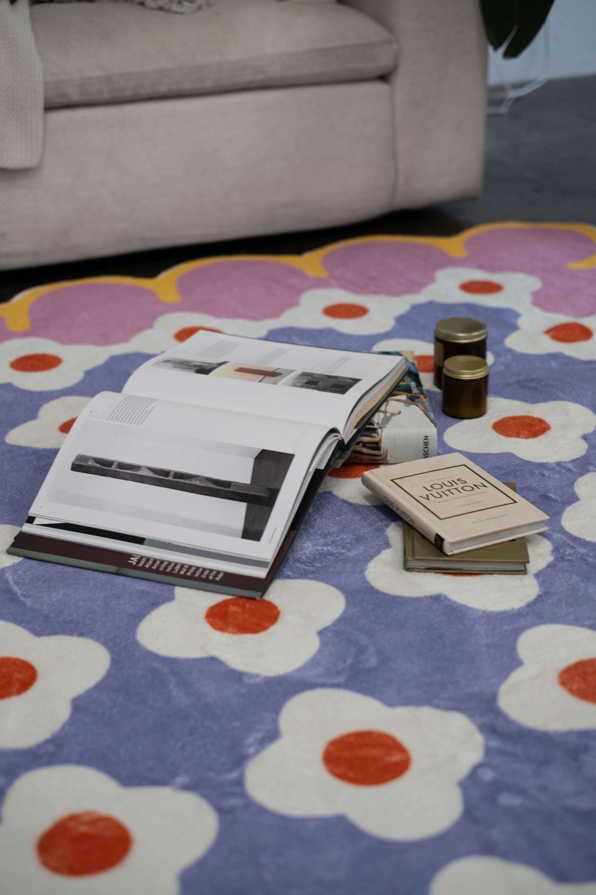 Detail of the pink and purple floral rug with open books and candles on top.