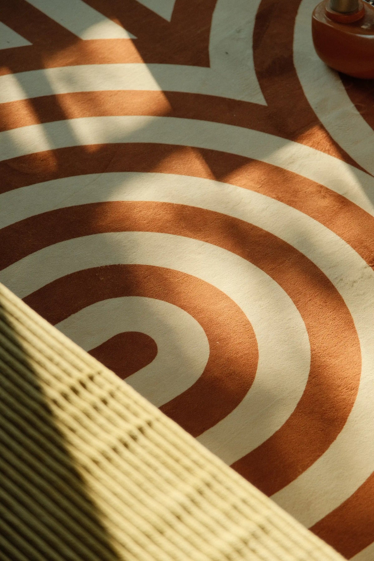 Curvy brown stripes design rug  pattern close-up beside a woven chair in warm natural light