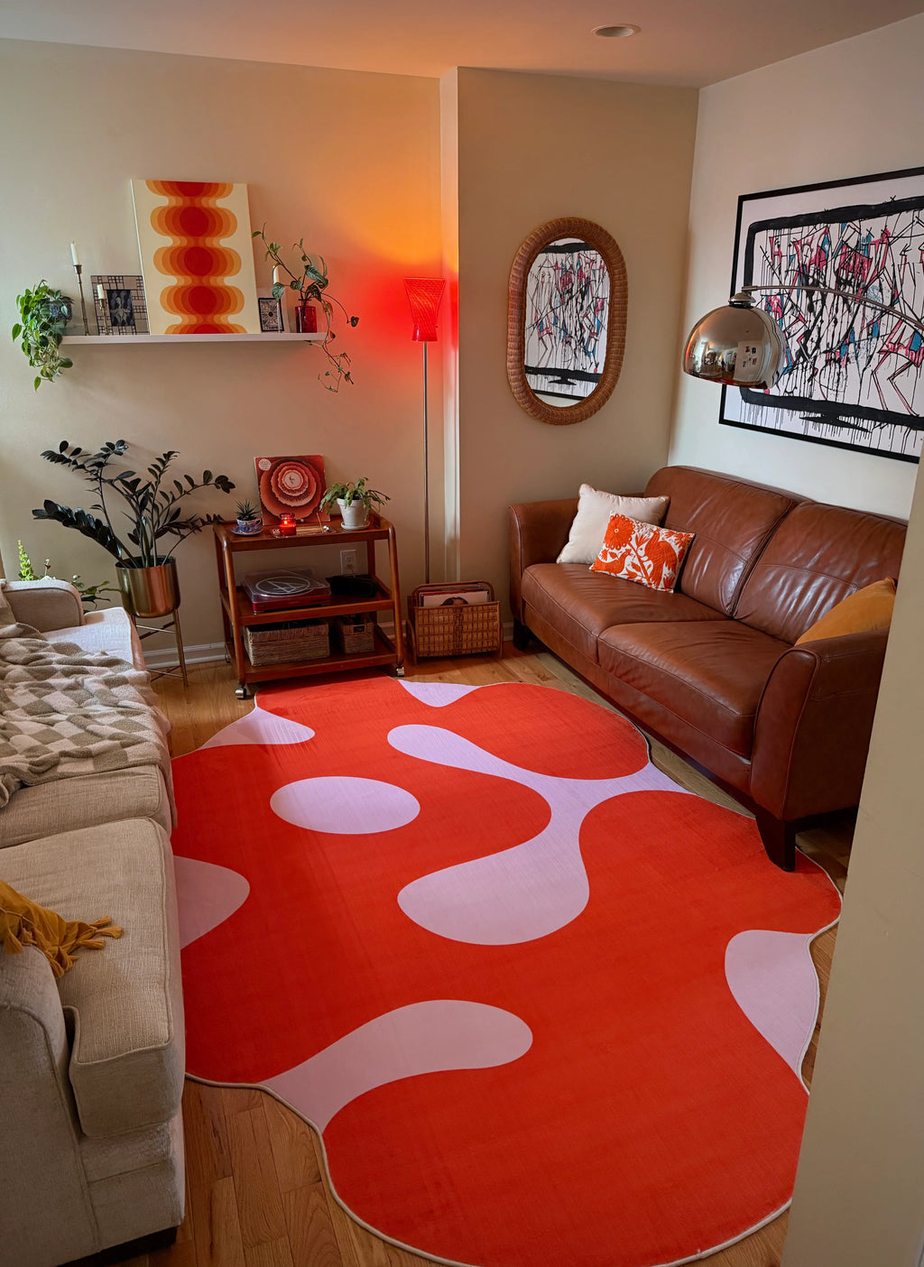 Living room with a brown leather sofa, orange moss abstract rug, and decorative items.