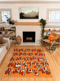 5' × 7' orange Squiggle Abstract Rug by Ariana Berman centered on a wood floor in front of a fireplace.