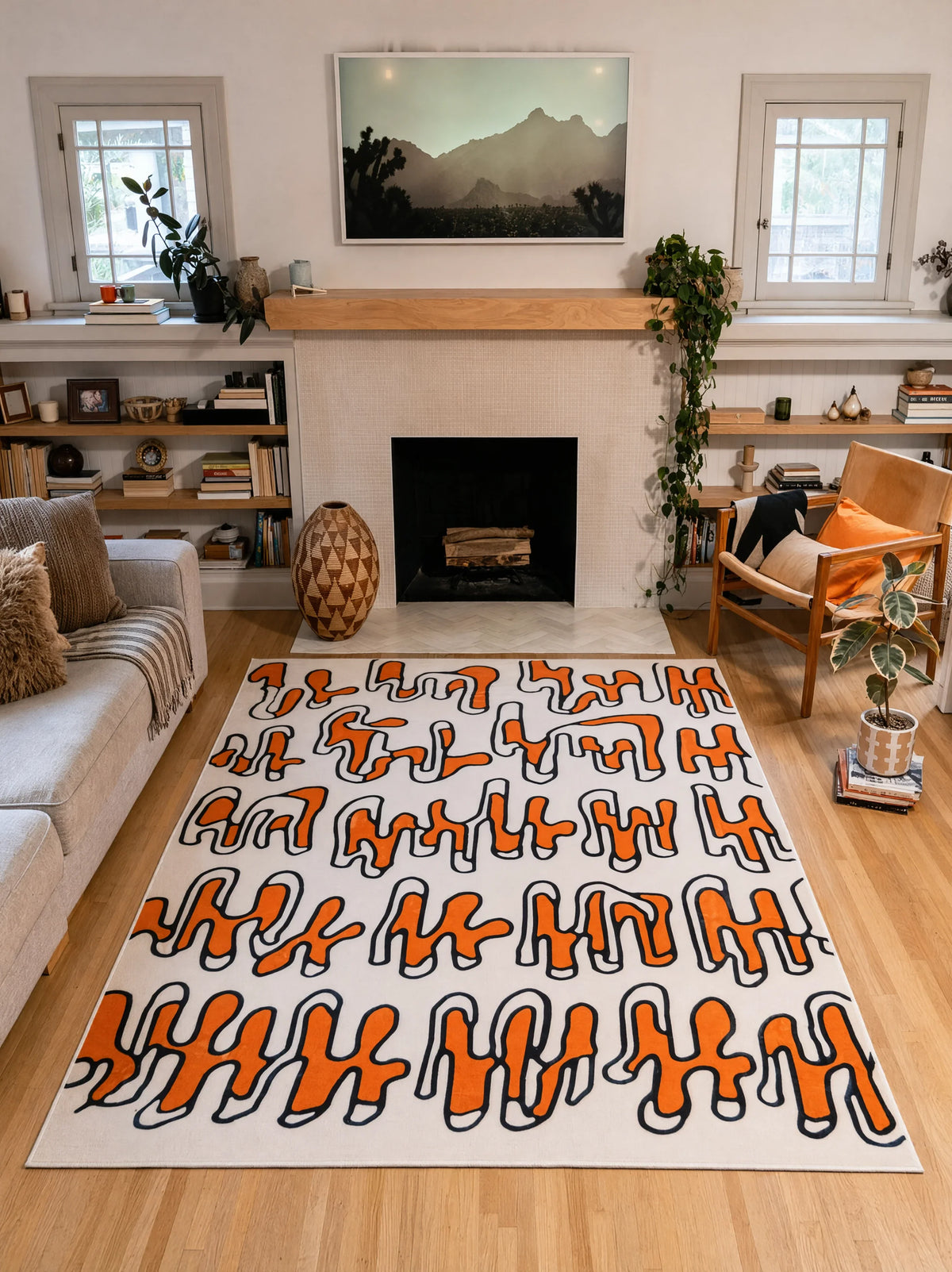 7' × 10' beige Squiggle Abstract Rug by Ariana Berman centered between a gray sofa and wooden armchair by a fireplace.