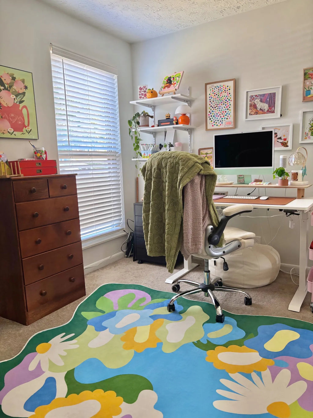 Botanical floral rug placed under a desk chair in a colorful home office with wall art and bright natural light.