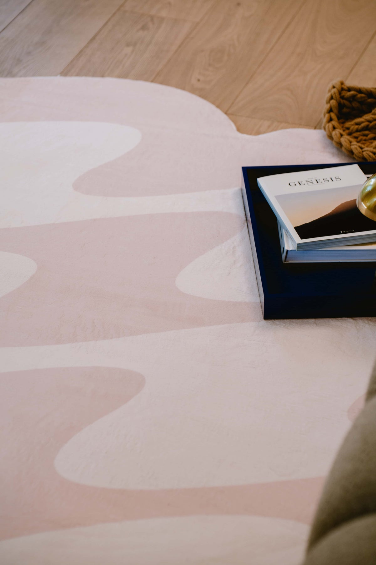 Soft fabric detail of beige pastel wavy rug, styled with books and golden accents.