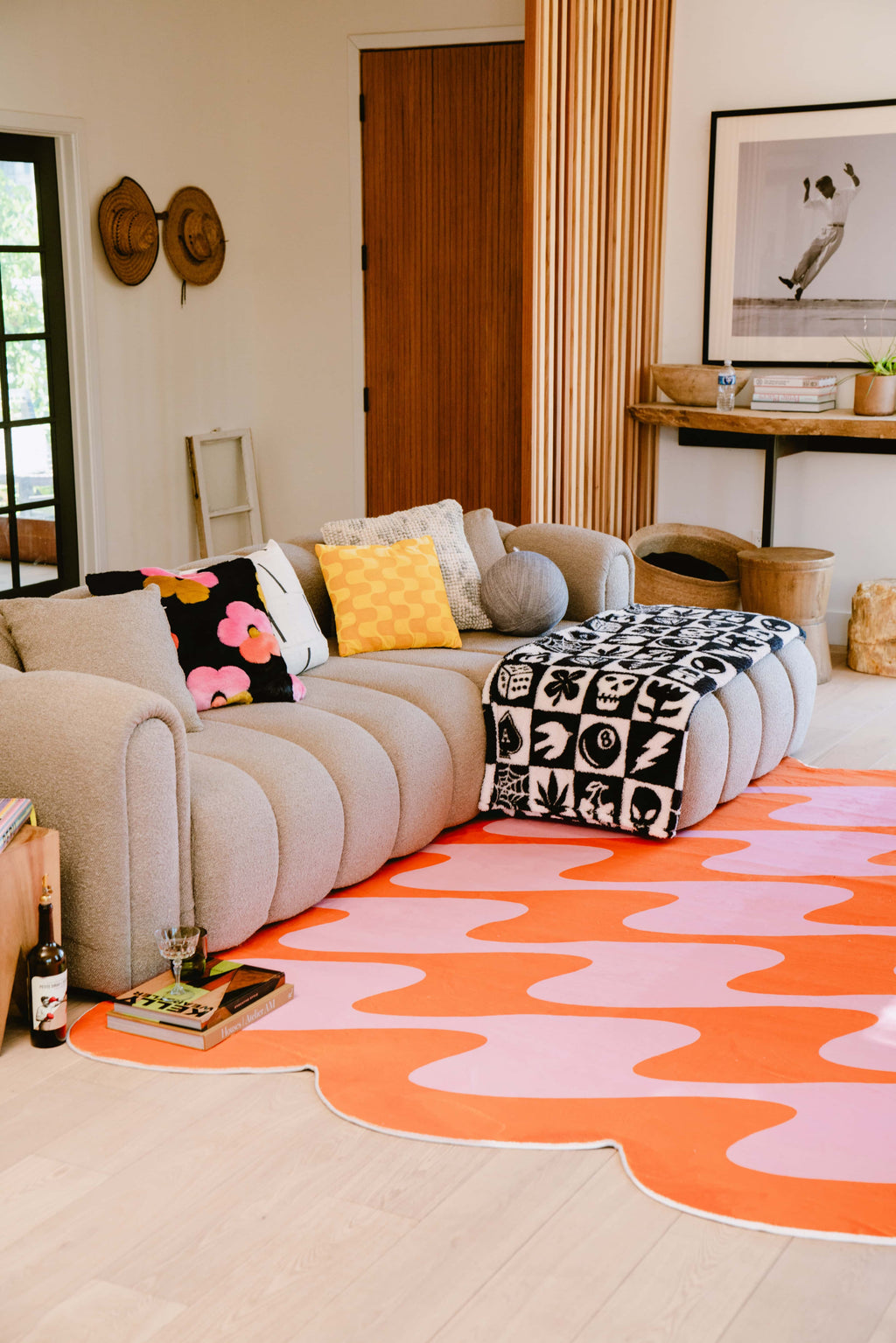 Wavy rug adds a bold pastel accent beneath cozy seating in a softly lit room with earthy tones and contemporary decor.