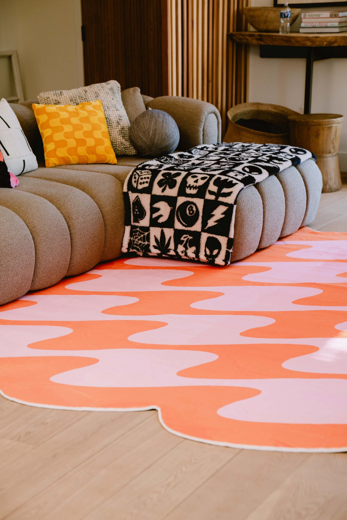 Closer view of pastel wavy rug’s organic edges and texture near curved modular sofa.