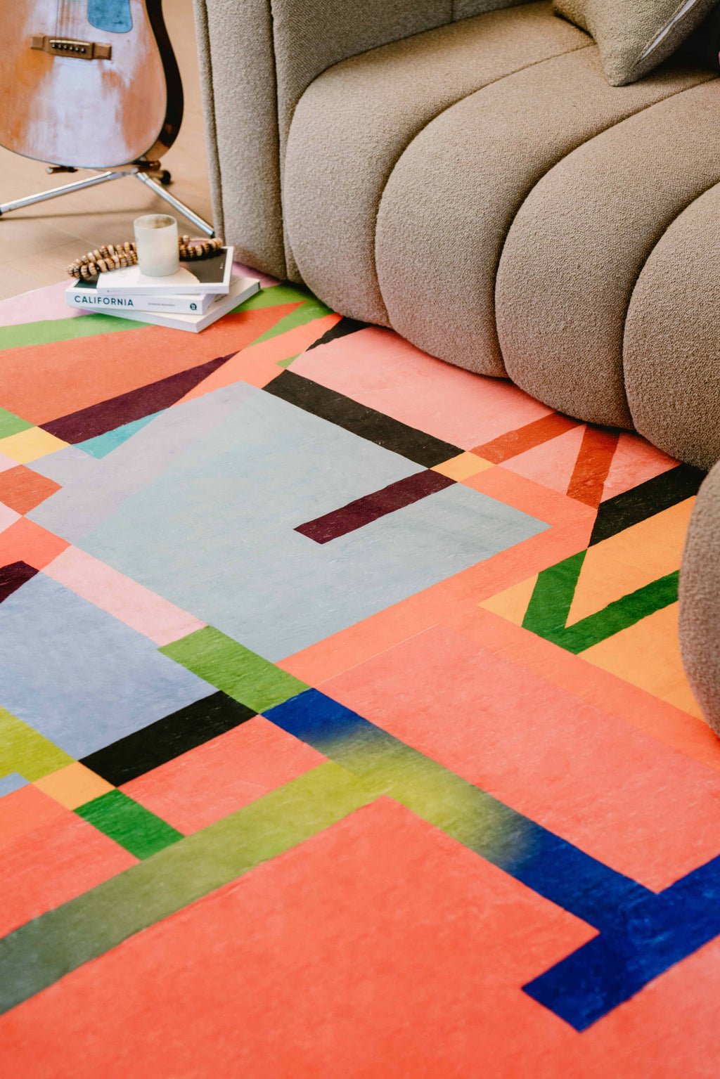 Close-up of multicolored block abstract rug placed in front of a textured sofa.