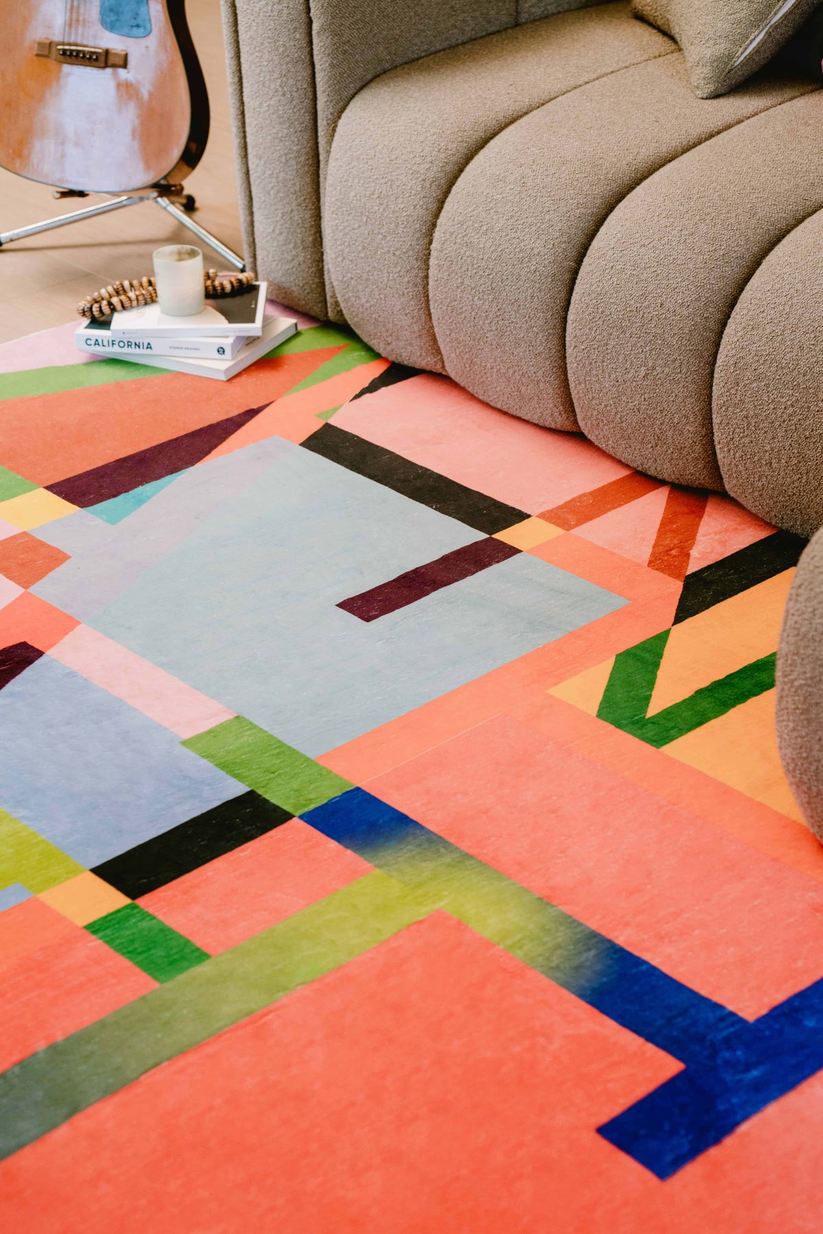 Close-up of multicolored block abstract rug placed in front of a textured sofa.