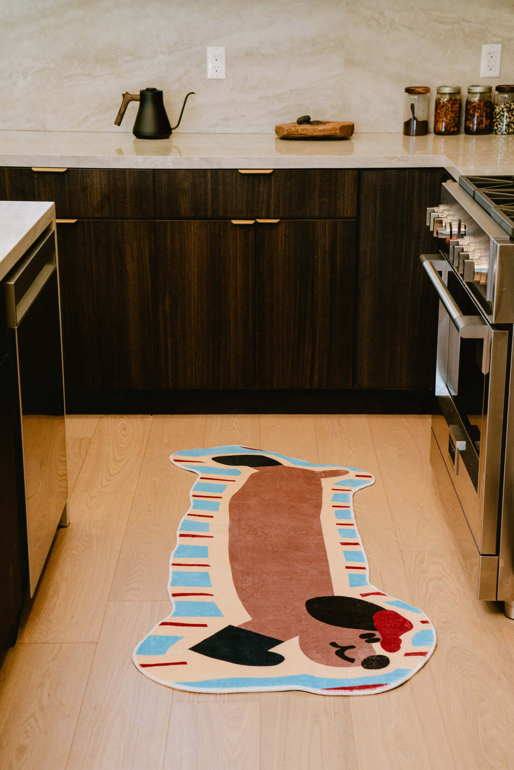 Brown dog runner rug placed in the kitchen between dark wood cabinets and stove, adding charm to the space.