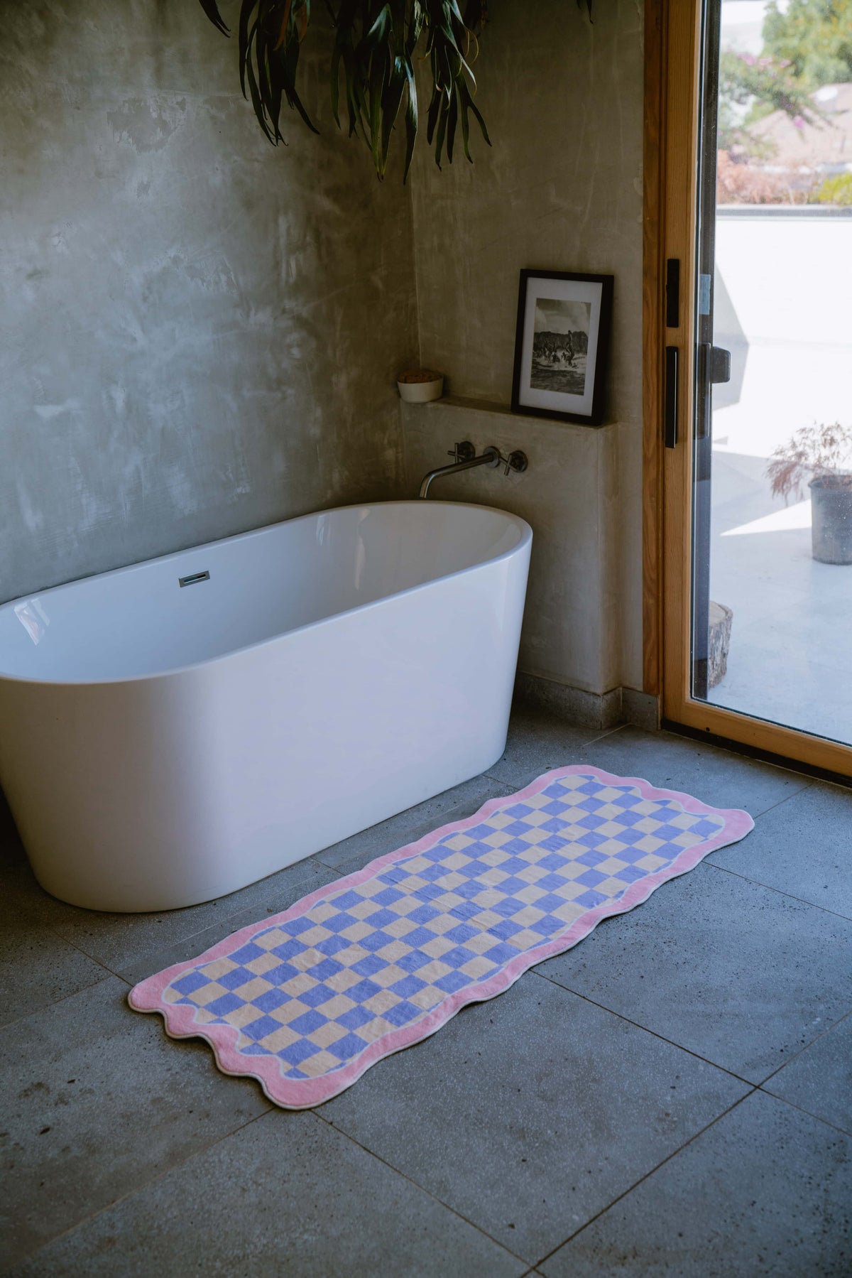 Pastel runner rug adding softness to a sleek grey bathroom with a freestanding tub.