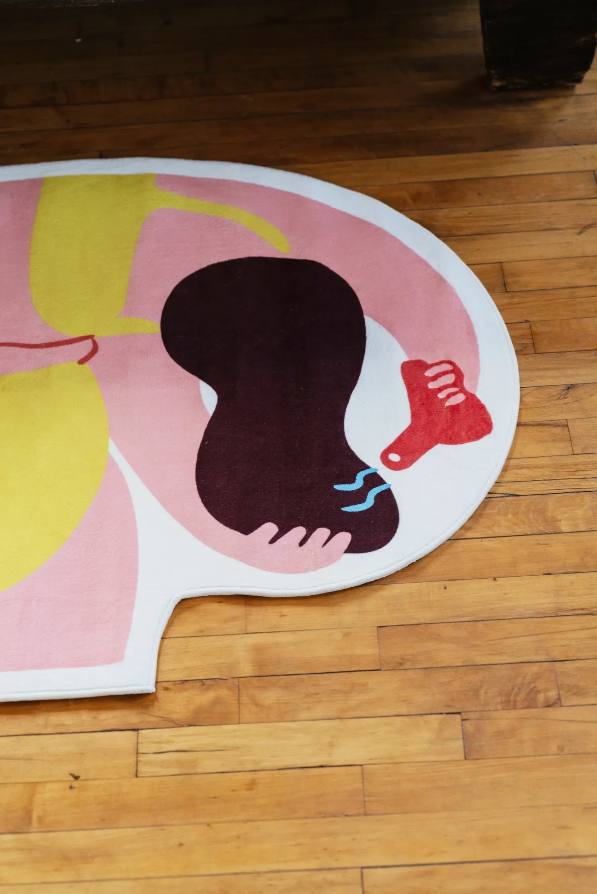Funky body art rug at foot of loft bed, side angle with rustic wood furniture and abstract figure design.