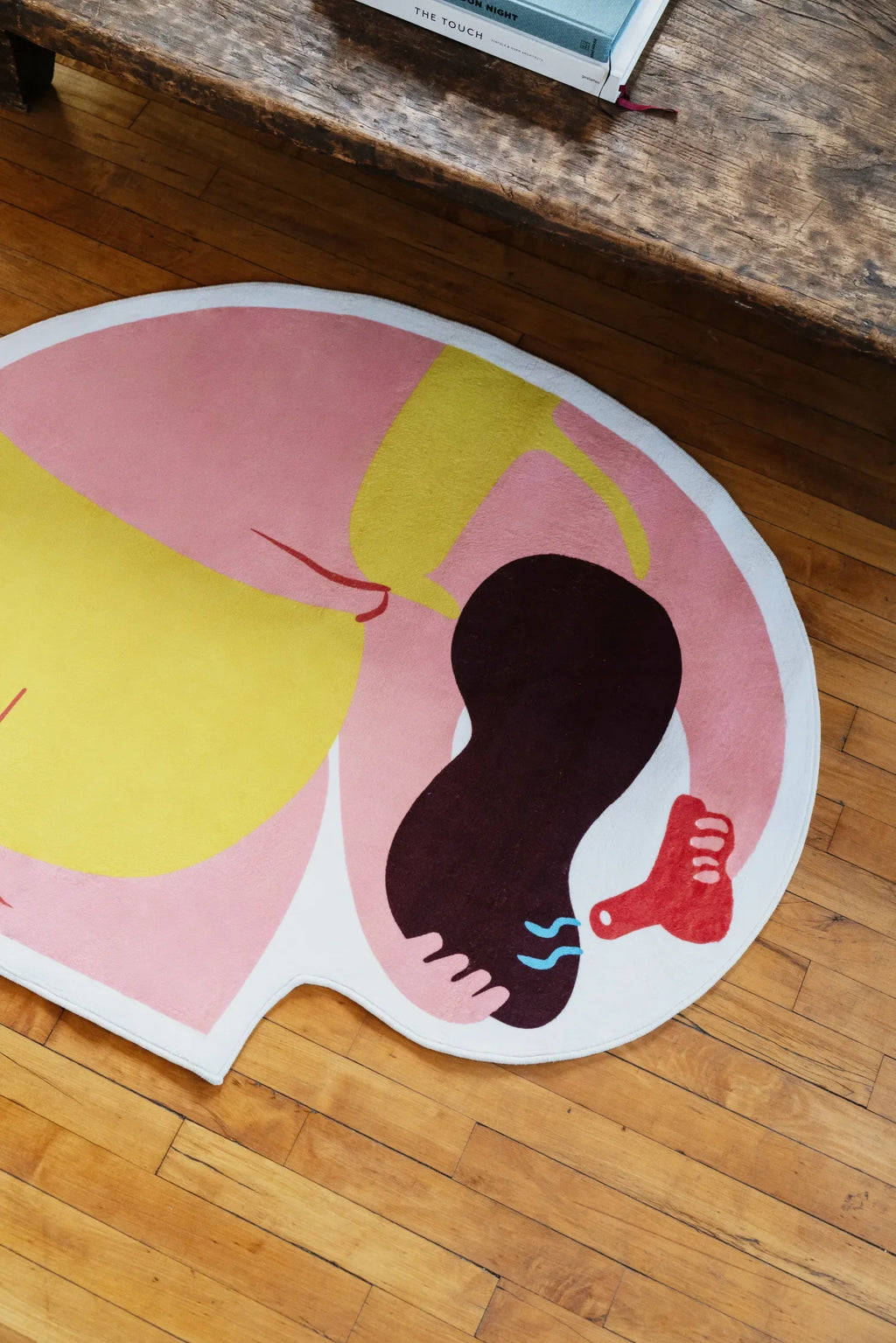 Overhead view of the Funky Body Art Rug by Nimei, showing its round shape and bold pink, yellow, and brown body illustration.