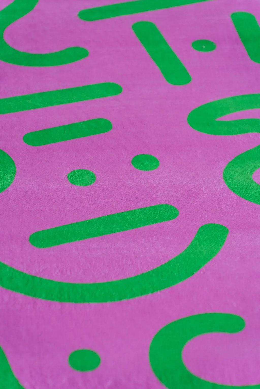Retro graphic rug in pink and green detail view, highlighting curved lines against warm wood floor.
