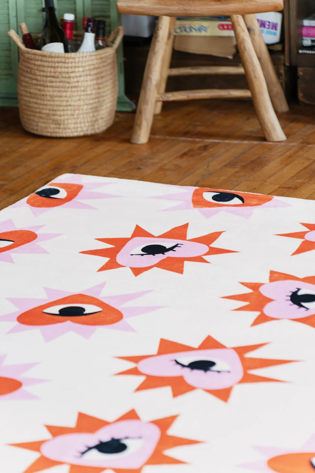 Heart Eye Pattern Rug placed on wood floor beside woven basket and stool, adding playful detail to the living room