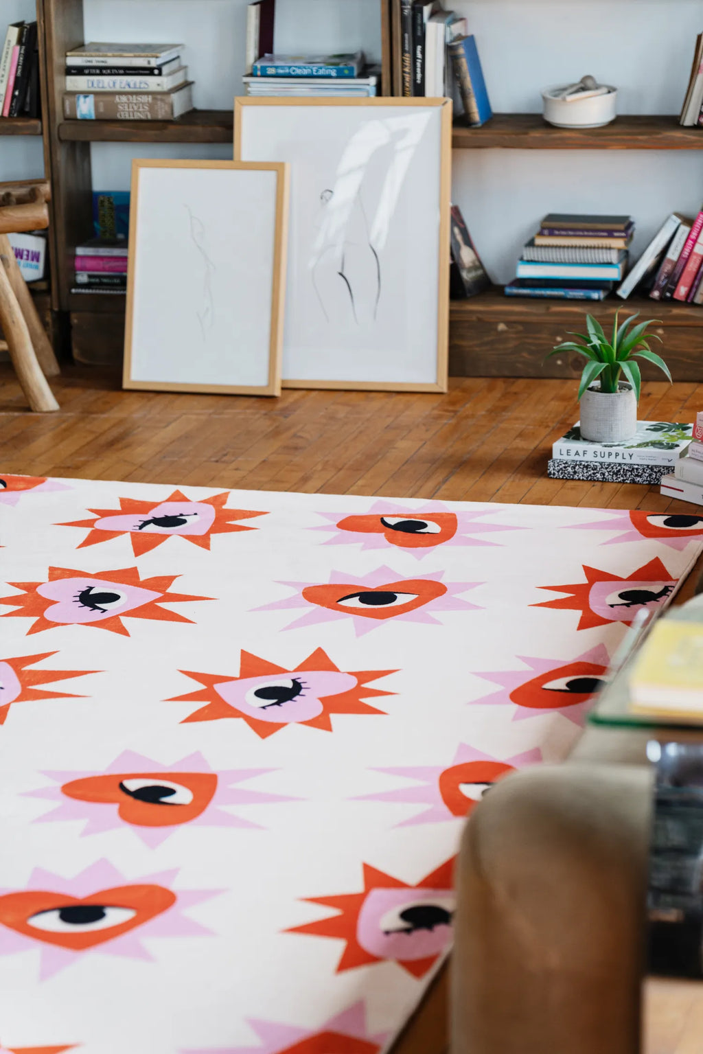 Playful rug with heart eye design styled near bookshelf, framed art and green plant in a bright living room