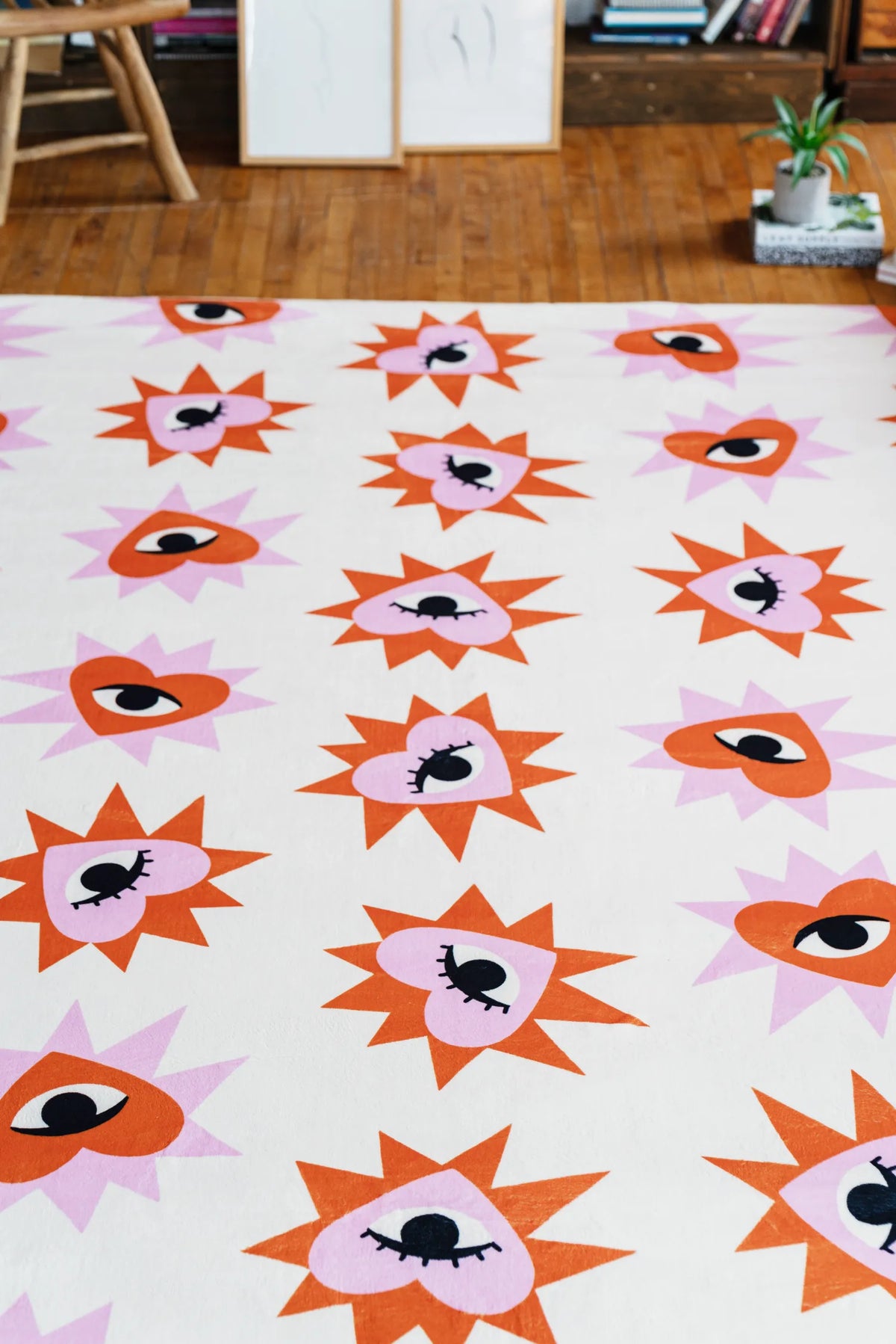 Close-up of colorful heart eye rug pattern spread across a wooden floor, highlighting bold graphic shapes in the living room