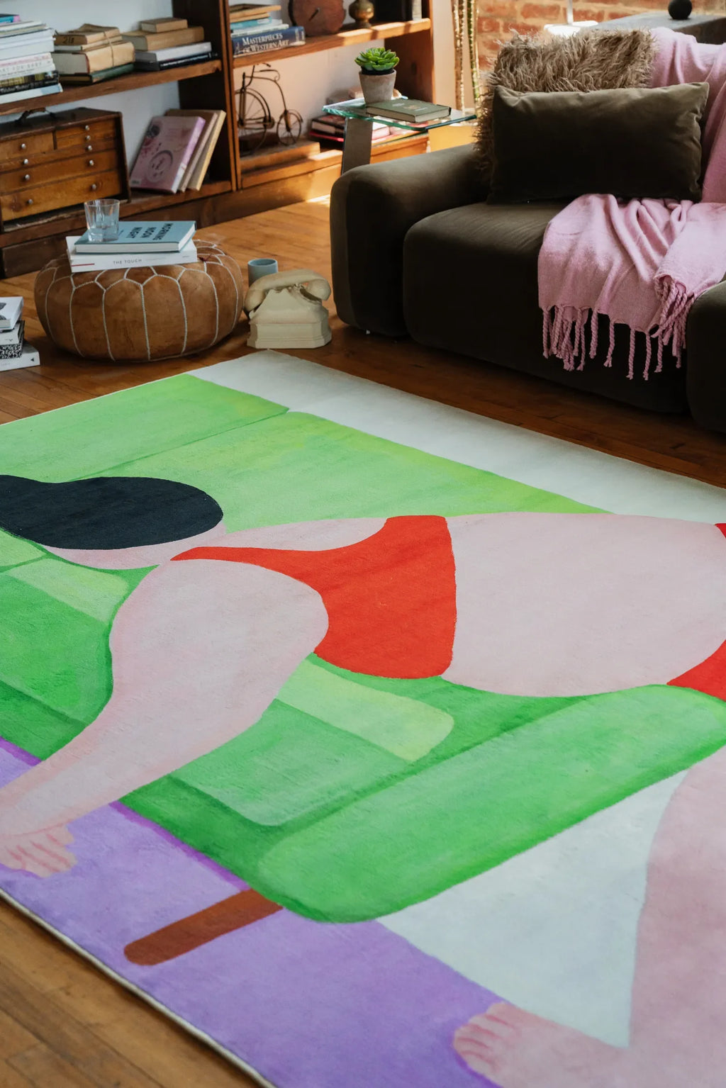 Close-up of abstract rug artwork showing bold shapes in red, green, and lilac, accenting the polished wooden floor.