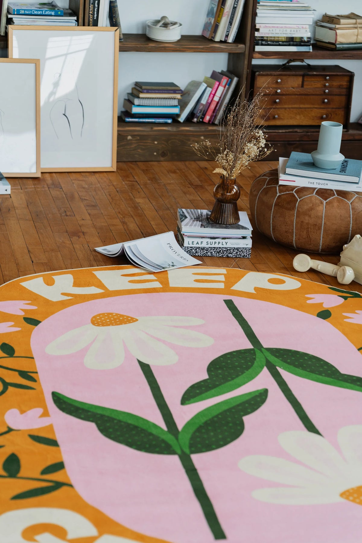 Modern area rug with daisy “Keep Growing” print resting on wooden floor in a cozy living room corner