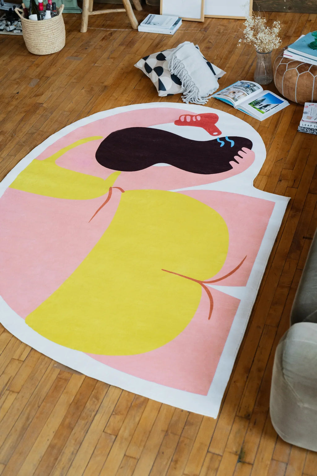Side perspective of the body art rug stretching across the wooden floor, bold yellow and pink tones catching natural light.
