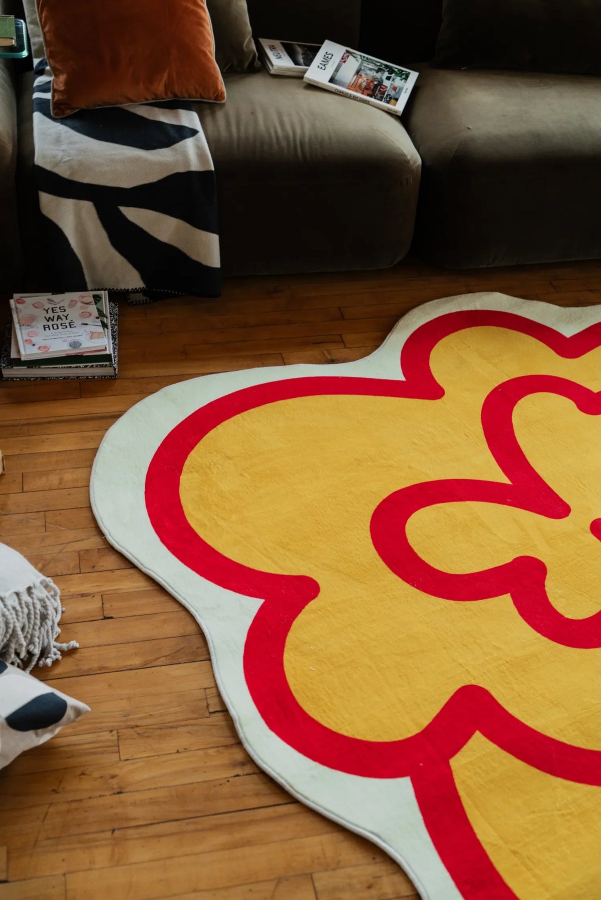 A funky flower shaped rug in yellow rests on wood floor beside a sofa with cushions, adding a lively accent to the living room.