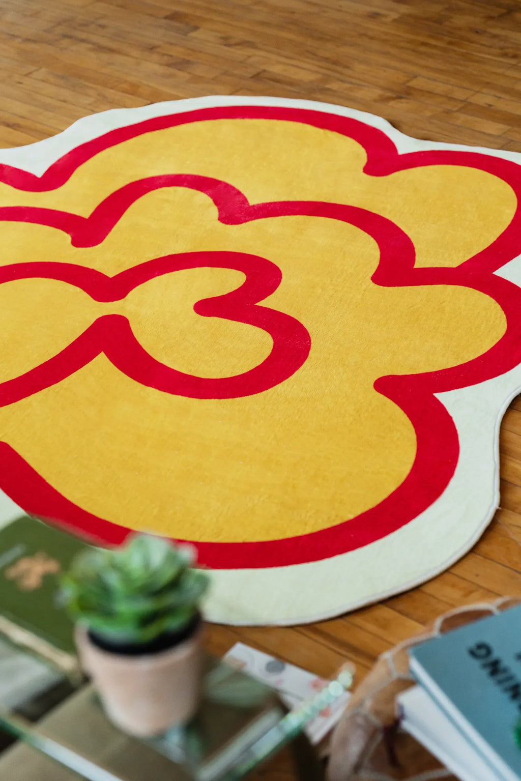 The yellow funky flower shaped rug rests casually on polished wood floor, its bold outline adding energy to the room.