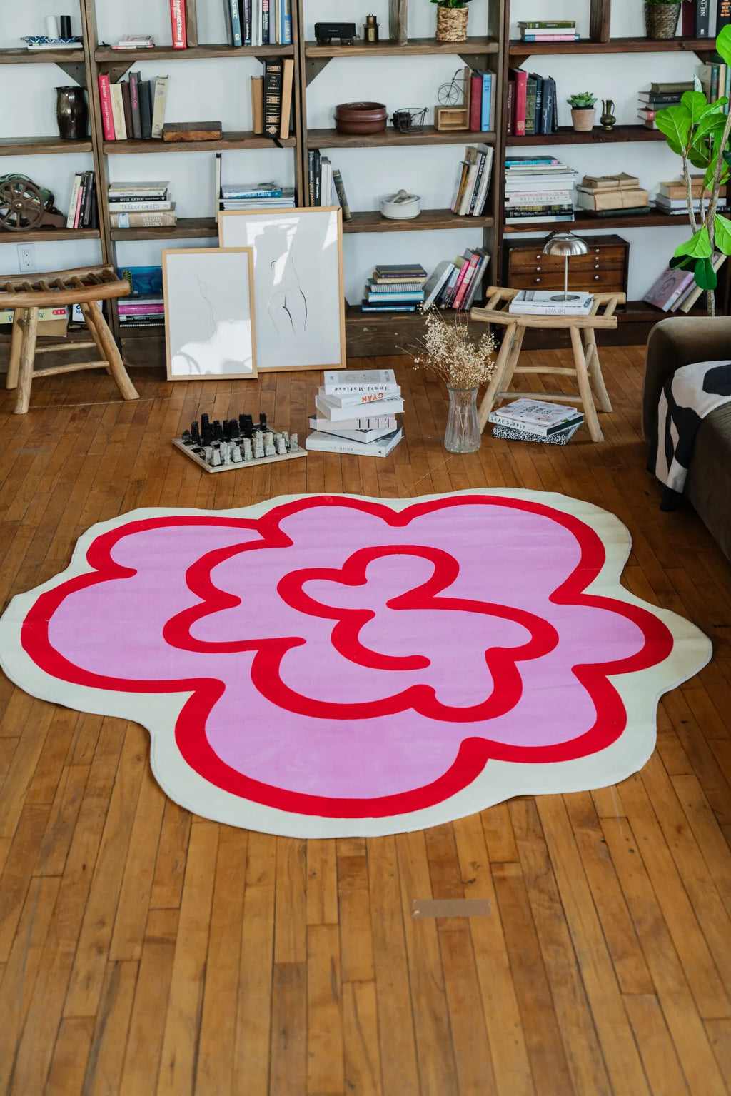 Pink Funky Flower Shaped Irregular Rug brightens the living room floor, standing out playfully against shelves filled with books.