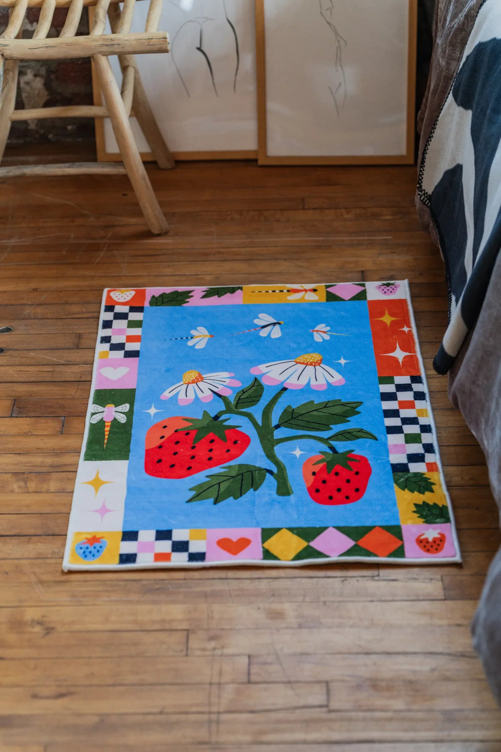 Playful rug with strawberries and daisies design styled flat on wood floor making a bright focal point in the bedroom interior