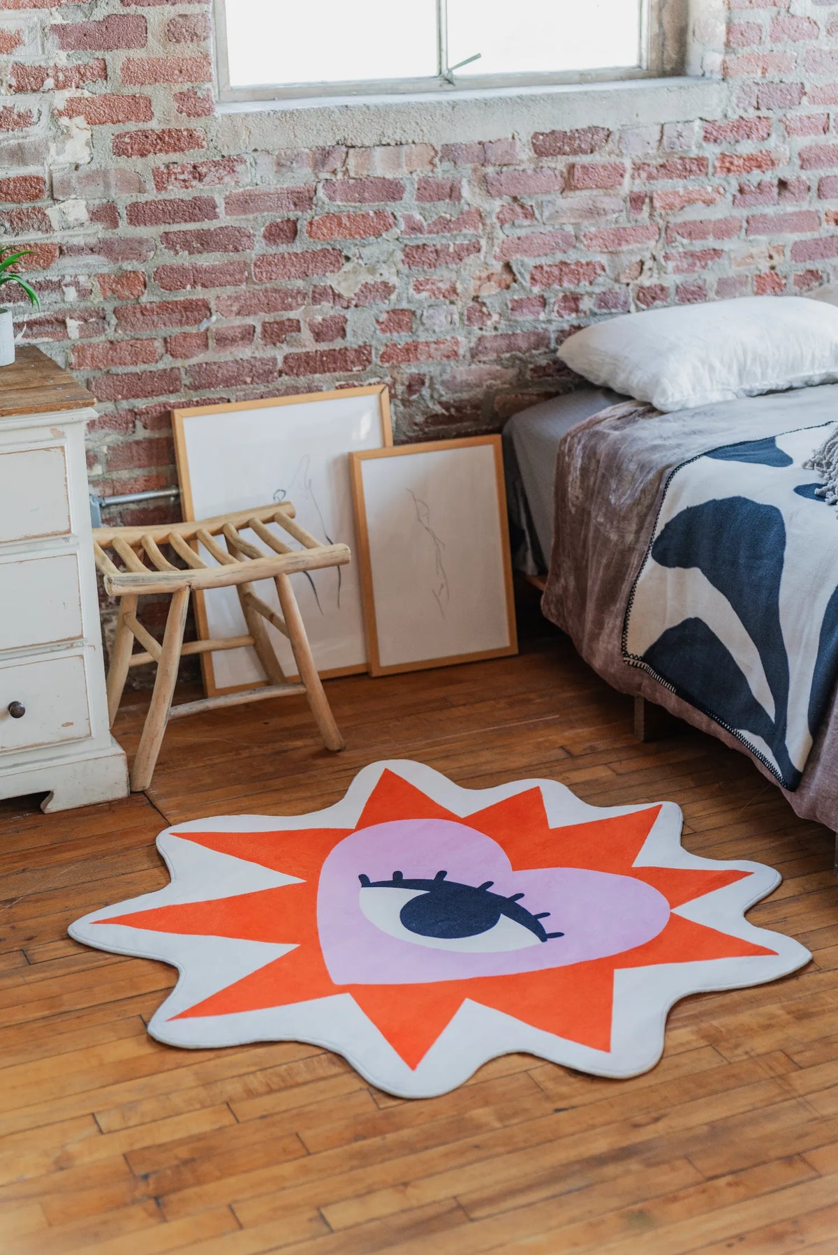 Colorful star-shaped rug with a heart and eye design on a wooden floor.