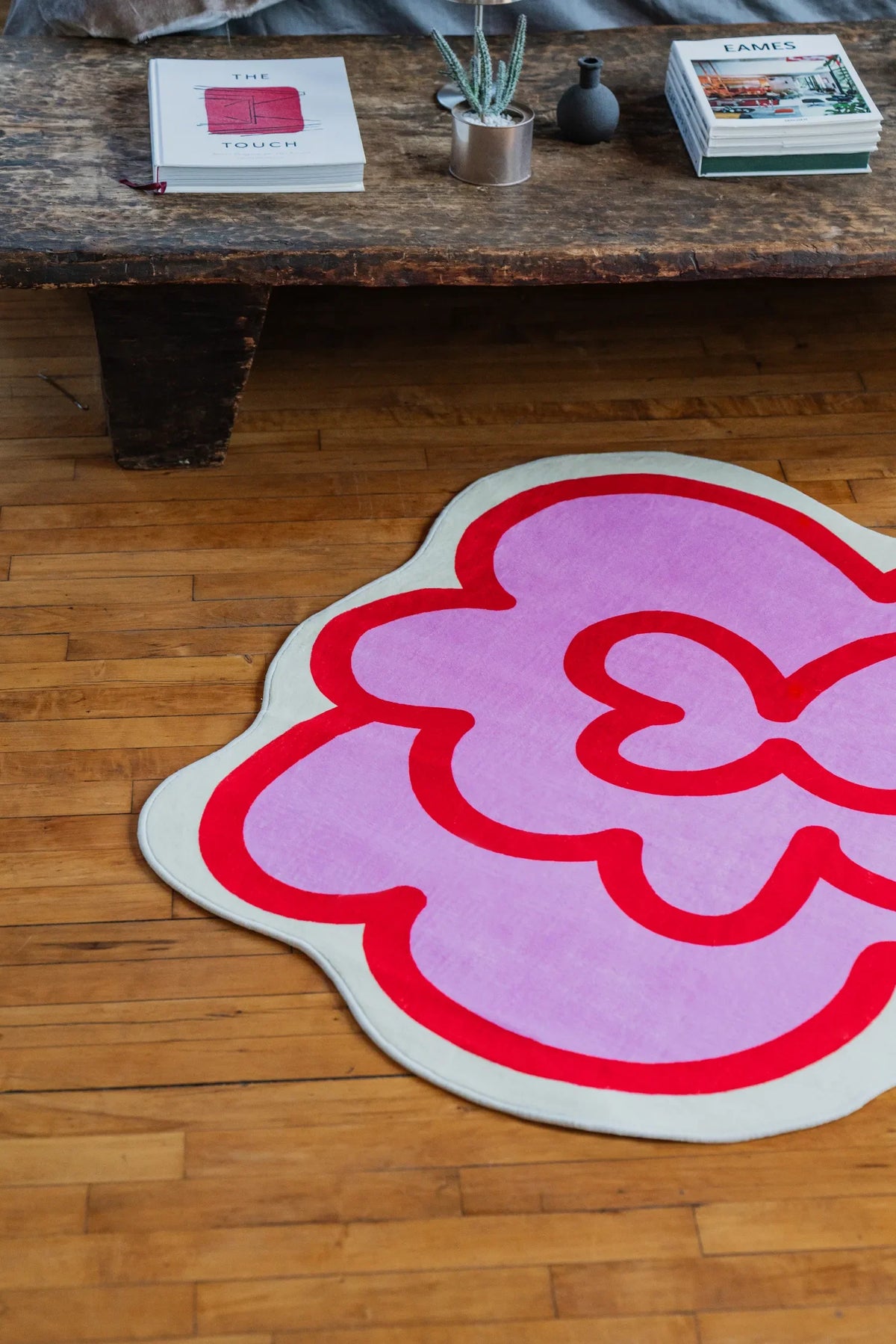 Pink Funky Flower Shaped Irregular Rug set near a rustic coffee table, adding a playful rug accent to the wood floor.