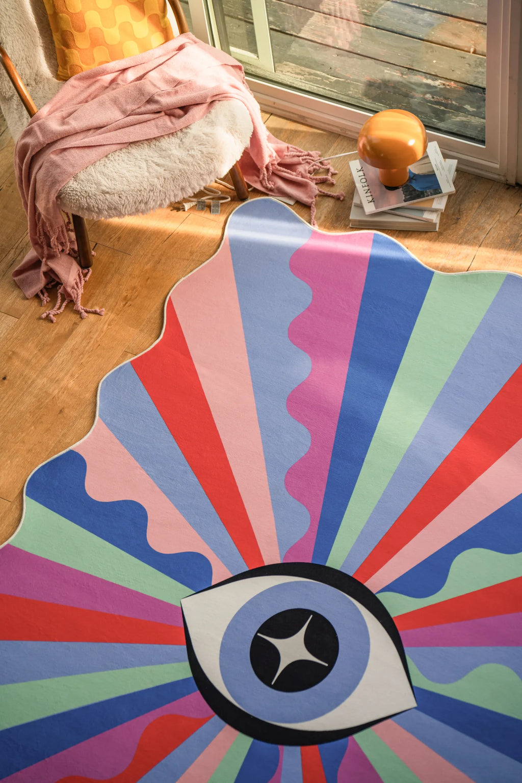 Funky eye rug placed near a window corner with sunlight casting onto the wood floor