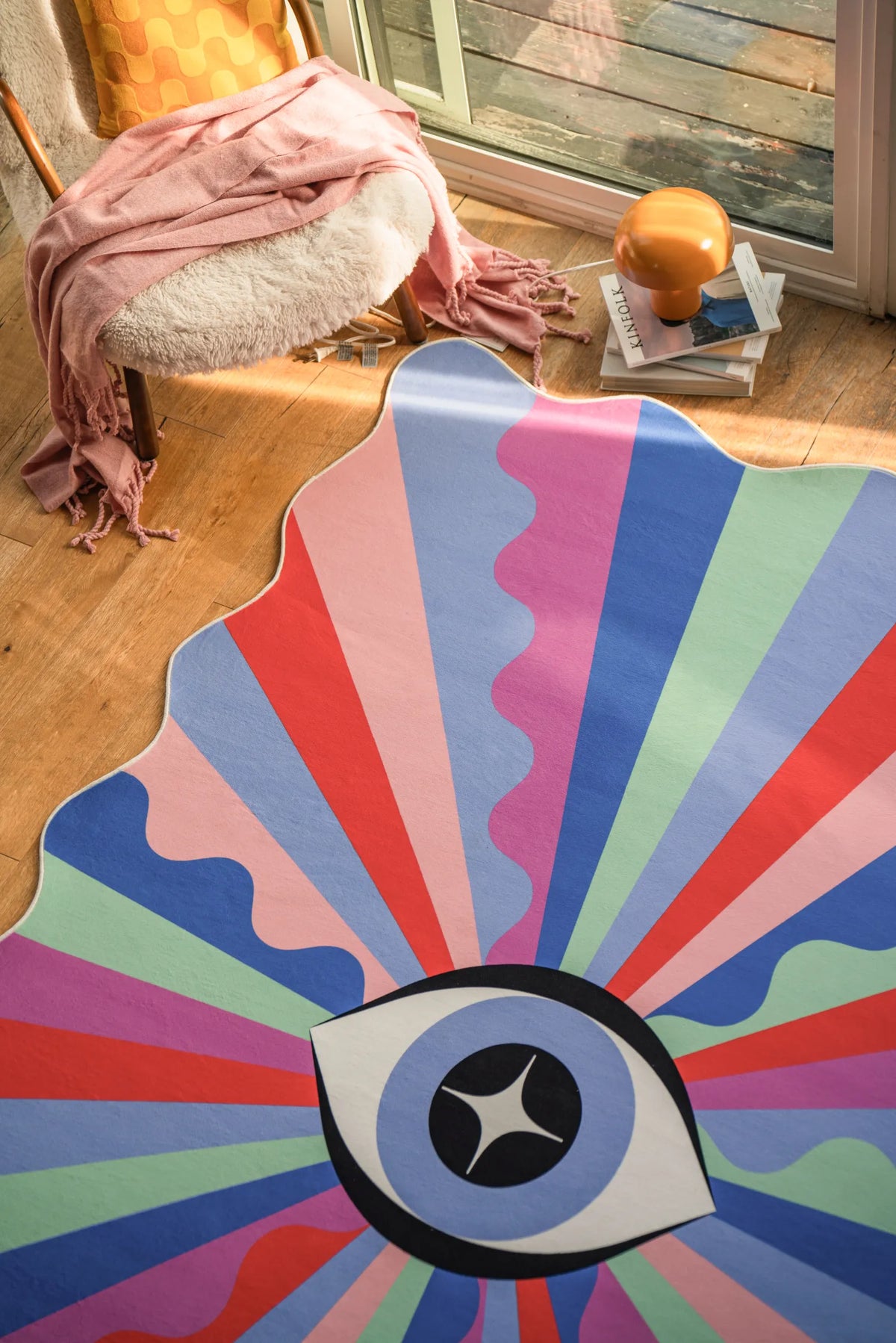 Funky eye rug placed near a window corner with sunlight casting onto the wood floor