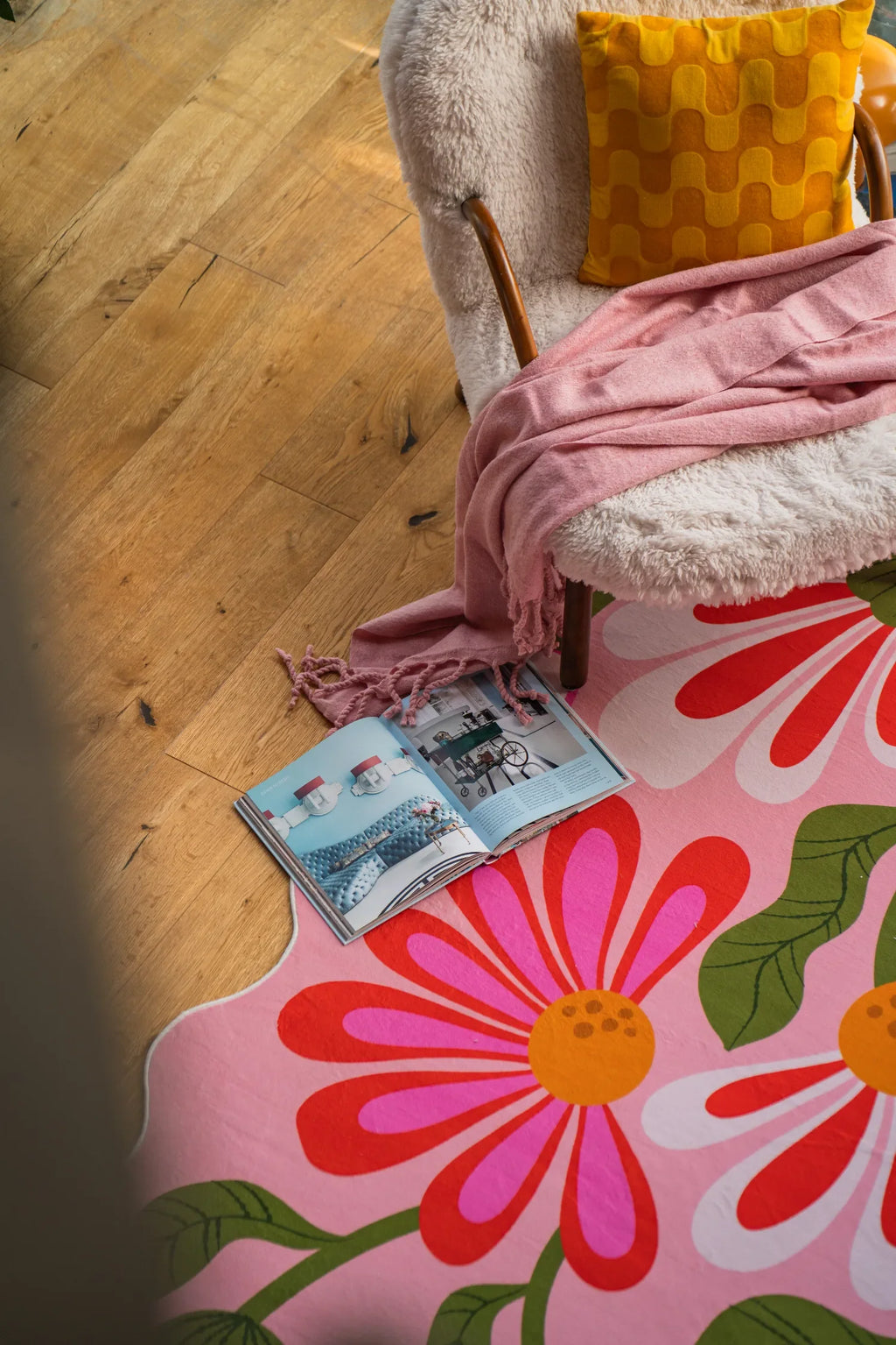 Pink floral wavy rug near a sherpa chair and wood floor in a relaxed corner setting.